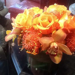 Orange and yellow floral arrangement in a dark vase