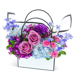 Mixed bouquet in a white handled basket with pink roses and blue flowers