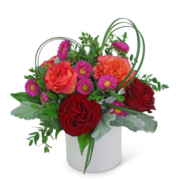 Red and orange roses with purple daisies in a white vase