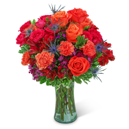 Bouquet of orange and red roses with carnations in a glass vase