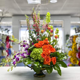 Orange roses and purple orchids in a low vase arrangement