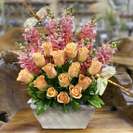 Peach roses and pink snapdragons in a rectangular stone vase