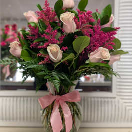 Pink roses and magenta filler in a glass vase with a pink ribbon