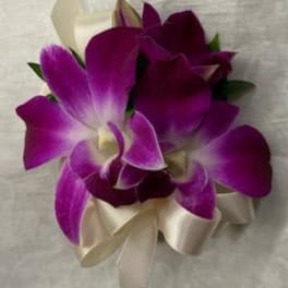 Purple orchid corsage with cream ribbon on a light fabric background