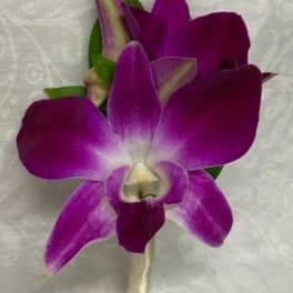 Purple orchid boutonniere with green accents on a wrapped stem