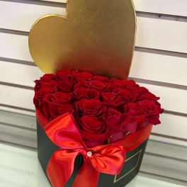 Heart-shaped box filled with red roses and tied with a red ribbon
