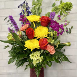 Colorful mixed flower arrangement in a tall burgundy vase