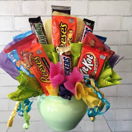 Candy bouquet in a green vase with assorted chocolate bars and ribbons