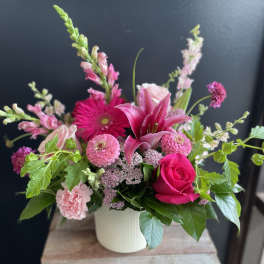 Pink mixed flower arrangement in a white vase