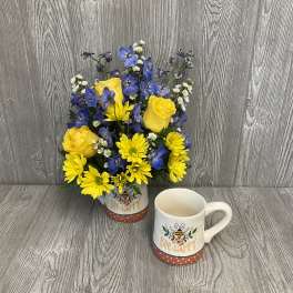 Yellow and blue flowers in a bee-themed mug, with a matching mug beside it.