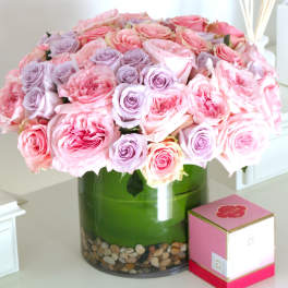 Pink and lavender roses arranged in a green glass vase.