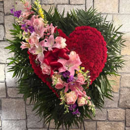 Heart-shaped floral spray with pink lilies and roses on a stand