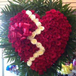 Heart-shaped rose arrangement with a pink ribbon and white rose accent