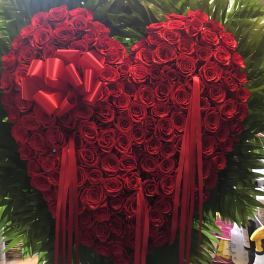 Heart-shaped red rose arrangement with ribbon accents