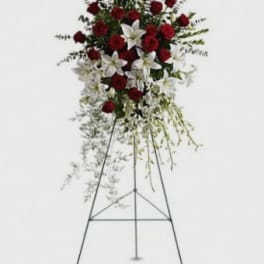 Standing floral spray with red roses and white lilies on a metal easel