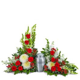 Red roses and white flowers arranged around a silver urn
