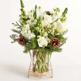 White floral arrangement in a gold geometric vase with pinecones