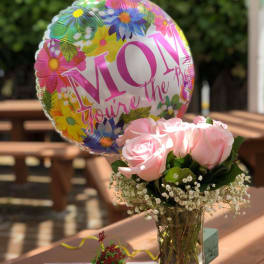 Pink roses in a glass vase with a floral Mother's Day balloon
