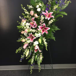Tall standing floral spray with pink lilies, roses, and purple accents