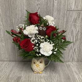 Red roses and white carnations in an owl mug vase