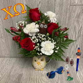 Red roses and white carnations in an owl mug with sports-themed charms.