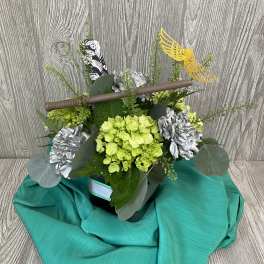 Floral arrangement with green hydrangeas, silver flowers, and a decorative sword topper