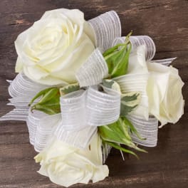 White rose corsage with sheer ribbon on a wooden surface