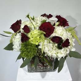 Red roses and white hydrangeas in a clear square vase