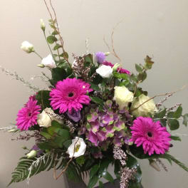 Mixed bouquet with bright pink daisies and white blooms in a gray vase