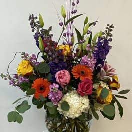 Colorful mixed bouquet in a glass vase with tall purple accents