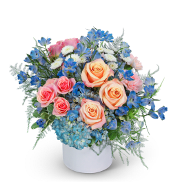 Bouquet of peach and pink roses with blue flowers in a white vase