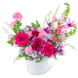 Pink and magenta floral arrangement in a white vase with silver disco balls