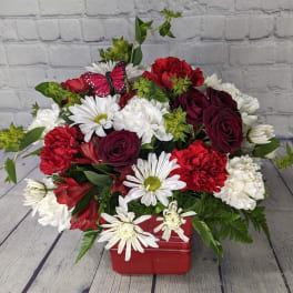 Red and white mixed bouquet in a red container with a butterfly pick
