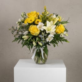 Yellow and white flower bouquet in a clear glass vase