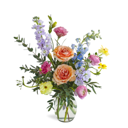 Mixed bouquet with peach roses and pastel flowers in a clear glass vase