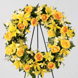 Yellow rose and lily wreath on a black stand