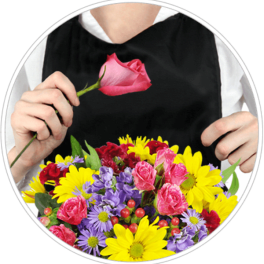 Person holding a pink rose above a colorful mixed bouquet