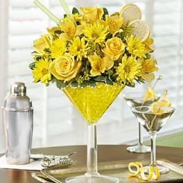 Yellow flower arrangement in a martini glass with lemon slices