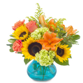 Sunflowers, orange lilies, and coral roses in a blue glass vase