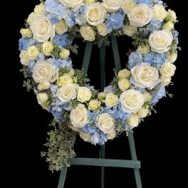 Heart-shaped floral wreath of white roses and blue hydrangeas on an easel