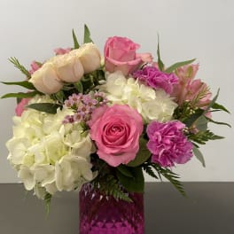 Pink and white flower arrangement in a magenta glass vase
