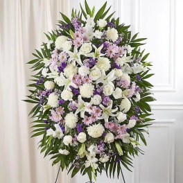 Standing funeral spray of white and lavender flowers on an easel
