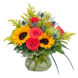 Bouquet of red roses and sunflowers in a glass vase