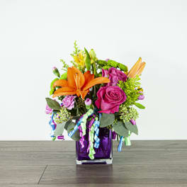 Bouquet of orange lilies and pink roses in a purple glass vase