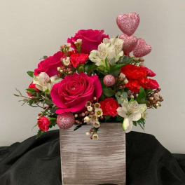 Pink and white flower arrangement in a square box with glitter heart picks