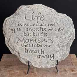 Round gray stone plaque with engraved inspirational quote on a metal display stand
