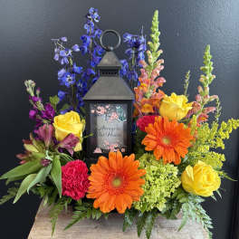 Colorful sympathy lantern arrangement with roses and gerbera daisies