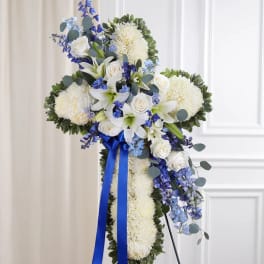 White floral standing cross with blue ribbon and blue flowers