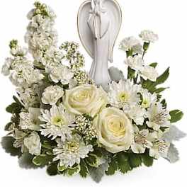 White floral arrangement with roses and daisies around an angel figurine
