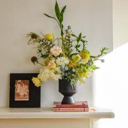 Mixed floral arrangement in a black vase with yellow and white blooms